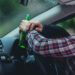 man holds a beer bottle while is driving a car