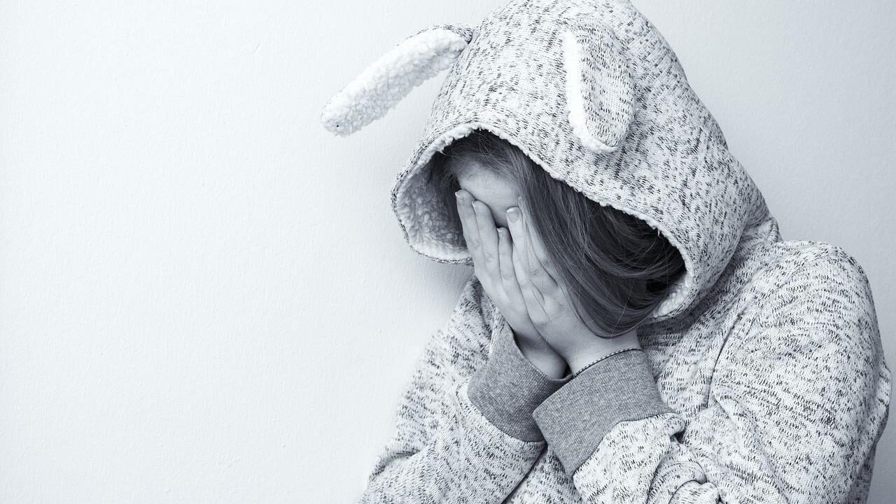 woman covering face victim of domestic violence