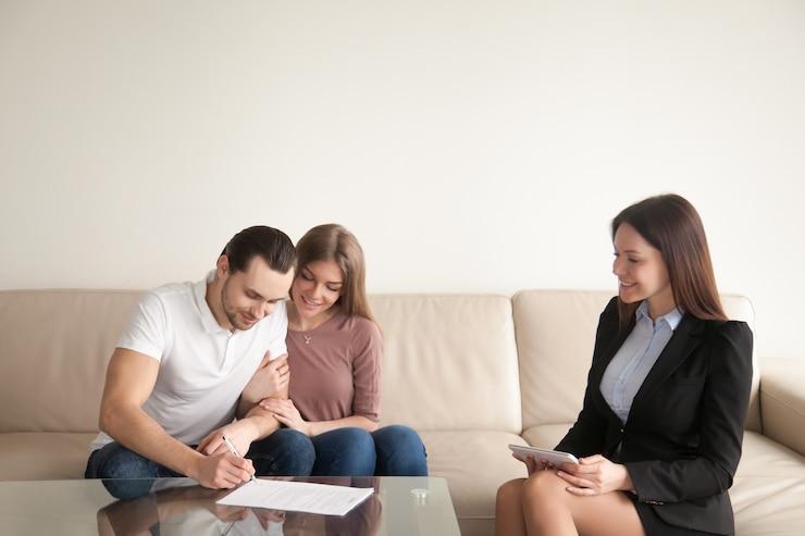 couple smiling signing paper in front of a lawyer